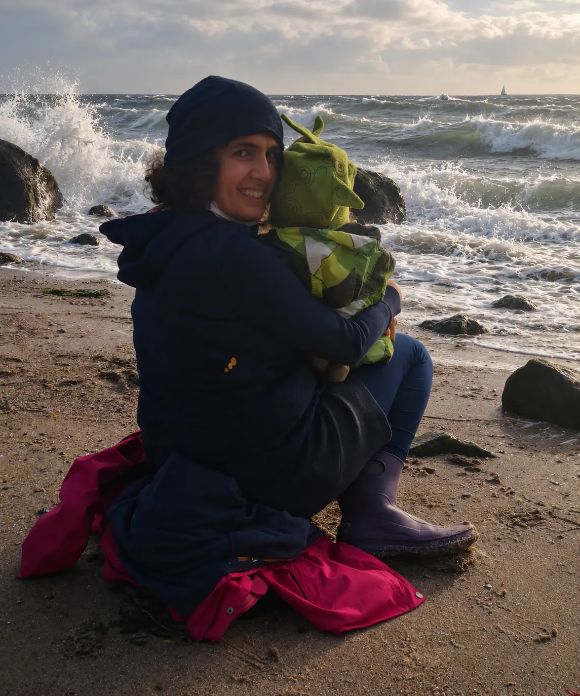 Kiran sitzt mit einem Kind am Meer